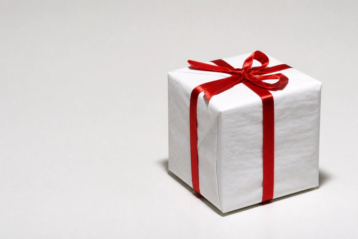 Regalo blanco con lazo rojo sobre fondo claro