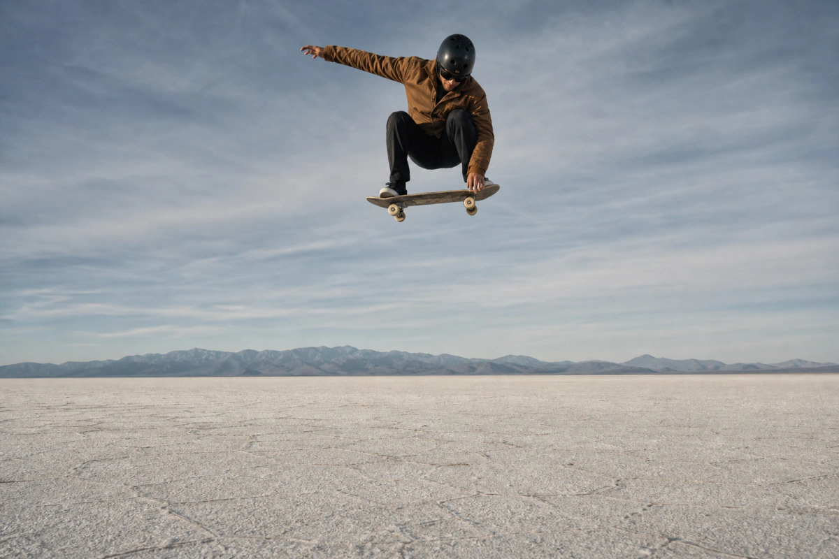 Skater suspendido sobre una llanura salina frente a montañas.